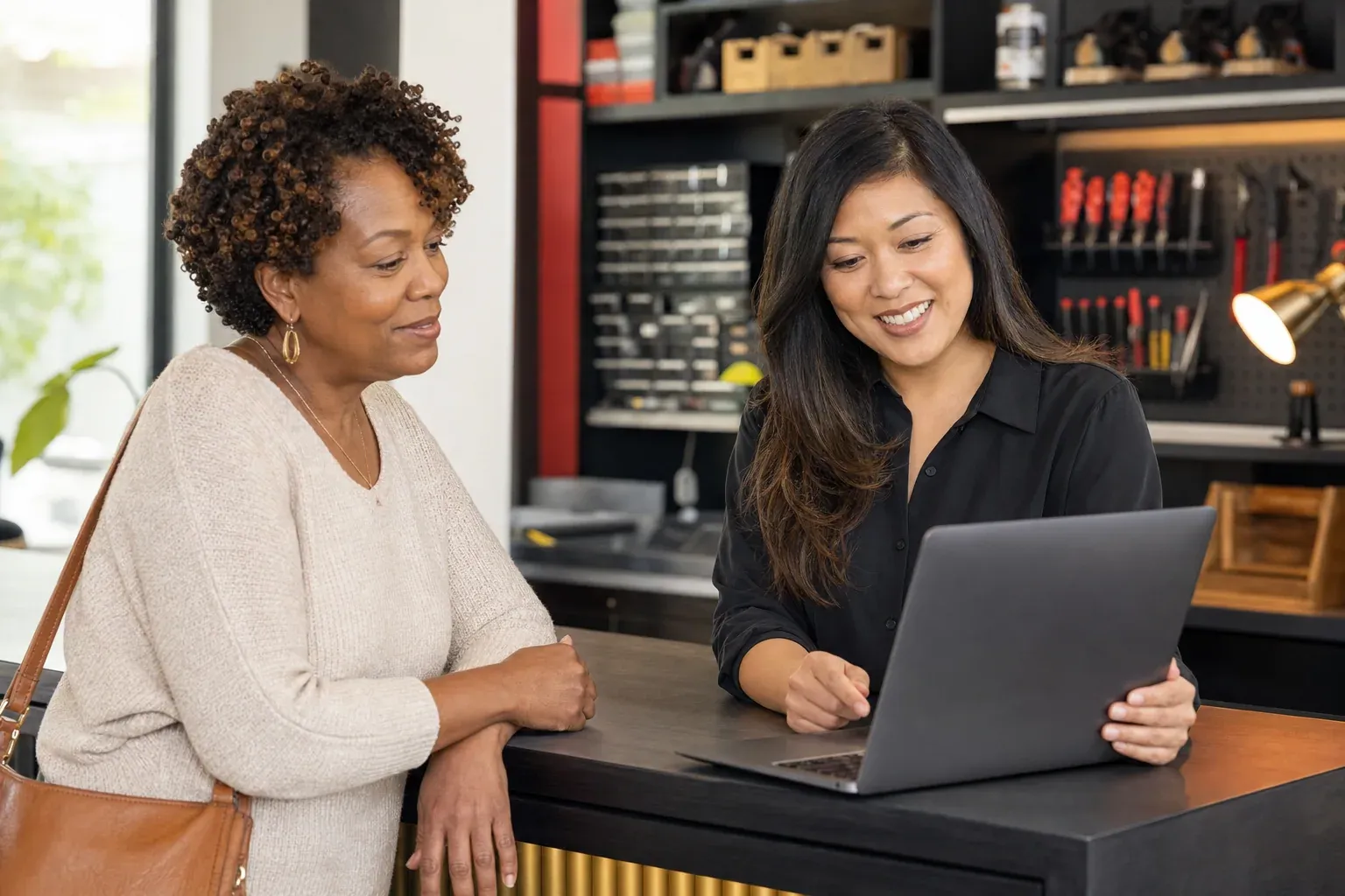 Black residential client reviewing her laptop with an Asian American computer technician